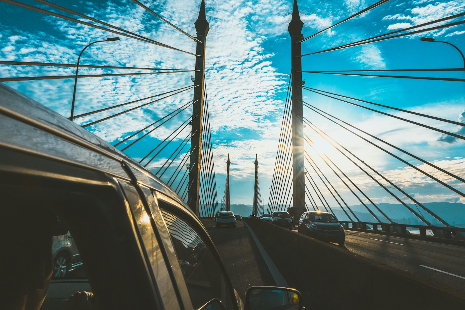 photography of vehicle traveling near suspension bridge during daytime